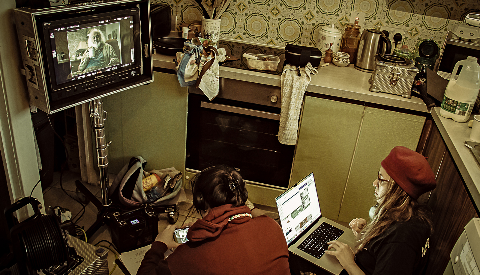 Man and woman in kitchen set looking at monitor